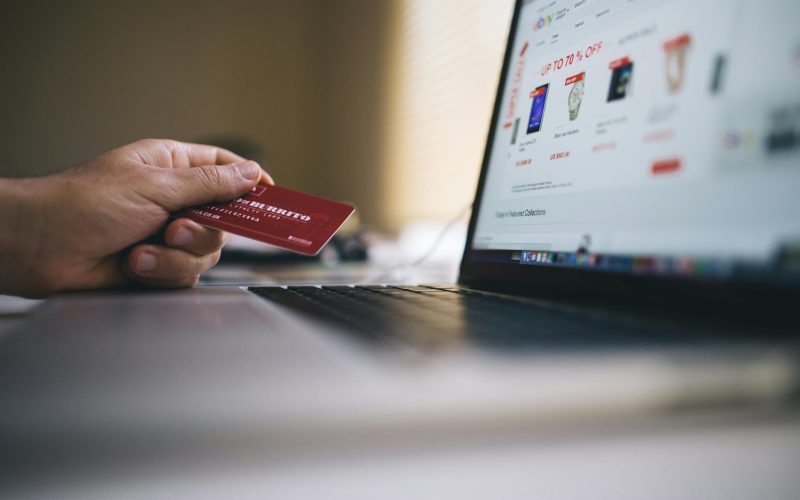 Person holding a credit card while shopping online on a laptop, indicating ecommerce transactions.